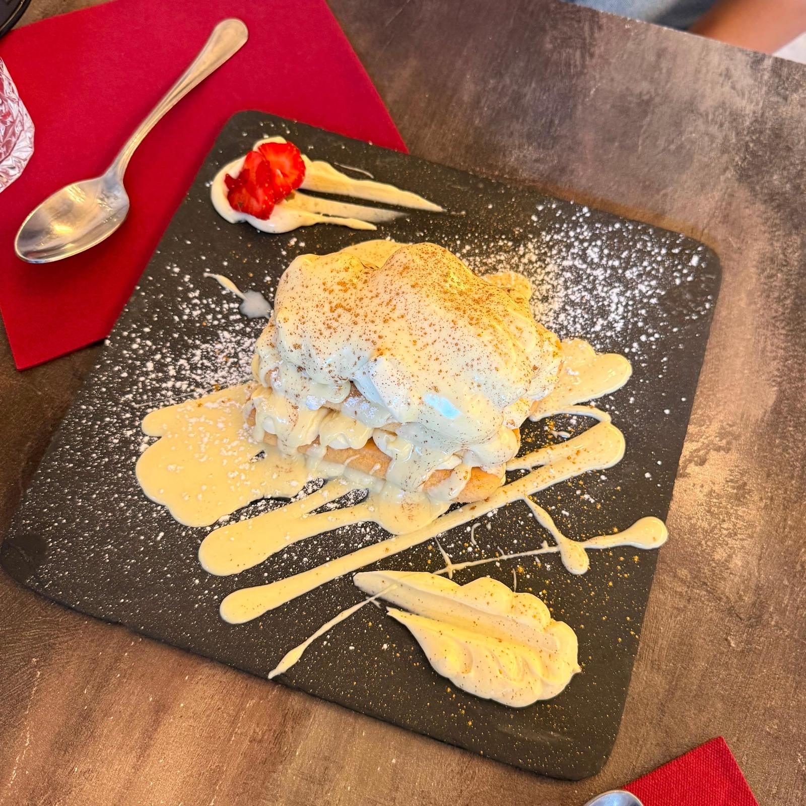 Tiramisù con crema colata a strisce su un piatto d'ardesia quadrato